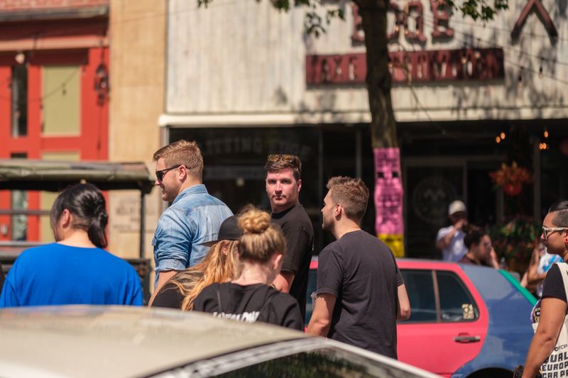 Three men standing together on a sunny street during the show